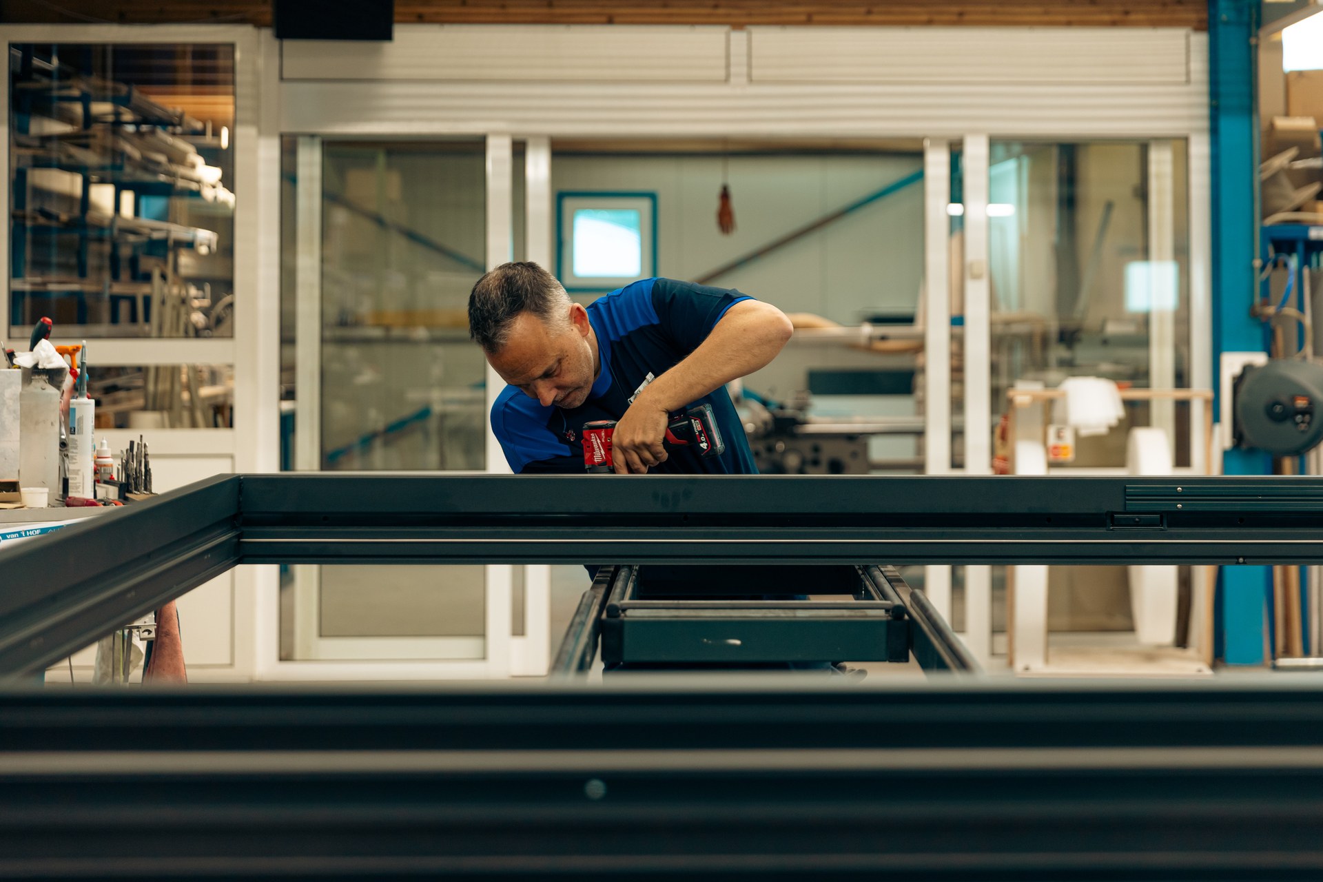 Vakman werkt aan een aluminium kozijn in de eigen werkplaats